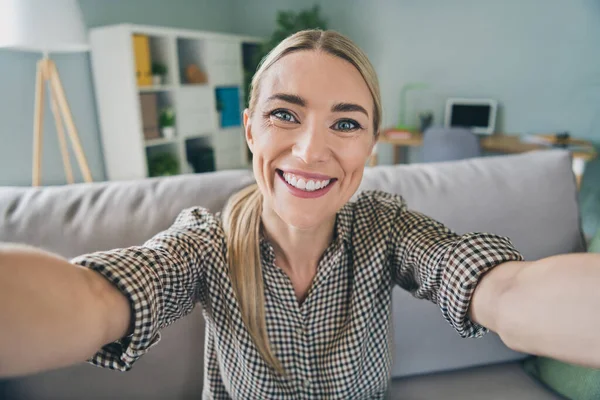 Foto de agradable optimista encantadora dama sentarse diván hacer selfie para su novio en viaje en la casa del hotel sala de estar —  Fotos de Stock