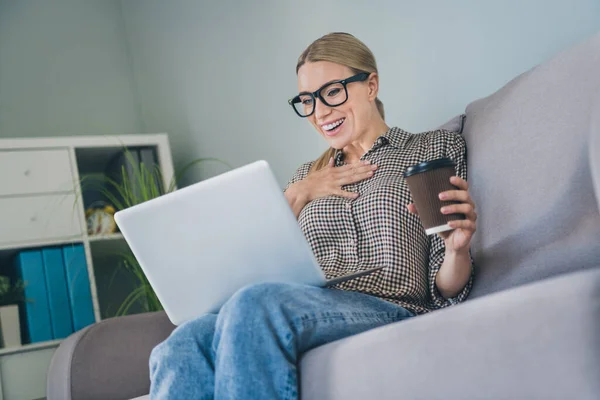 Foto de gerente divertido comerciante collar dama sentarse sofá reloj portátil comedia celebrar comida para llevar taza de bebida en el espacio de trabajo moderno —  Fotos de Stock