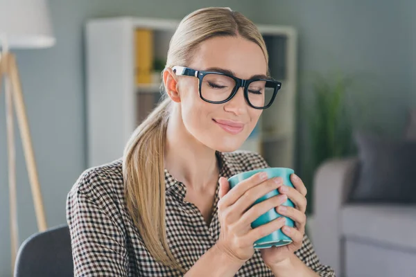Foto di positiva signora banchiere economista tenere tazza di latte caldo godere di profumo aromatico nel moderno spazio di lavoro — Foto Stock