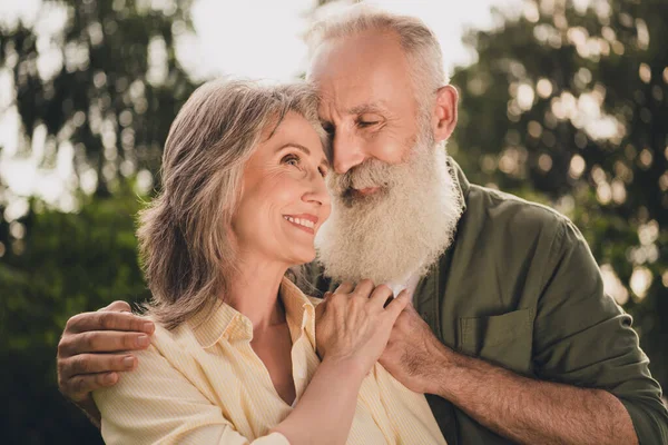 Foto de la optimista pareja de ancianos abrazo look desgaste camisa caminar en el parque al aire libre — Foto de Stock