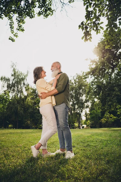 Foto de pareja jubilada encantadora positiva usar ropa casual caminar abrazos disfrutando el uno del otro sonriendo fuera de la calle urbana de la ciudad — Foto de Stock