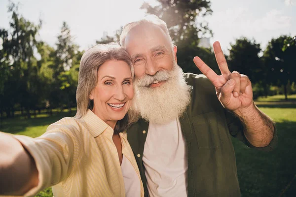 Foto de la pareja de edad cool mostrar v-signo do selfie usar camisa caminar en el parque al aire libre —  Fotos de Stock