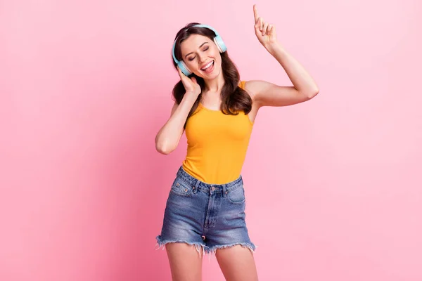 Photo of funny cute young woman wear yellow singlet listening music pointing finger isolated pink color background — Stock Photo, Image