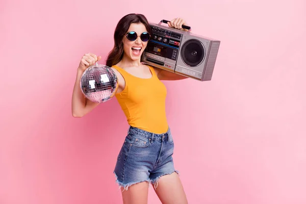 Bild av imponerad behornade unga dam klädd gul tank-top mörka glasögon håller bom box disco boll isolerad rosa färg bakgrund — Stockfoto