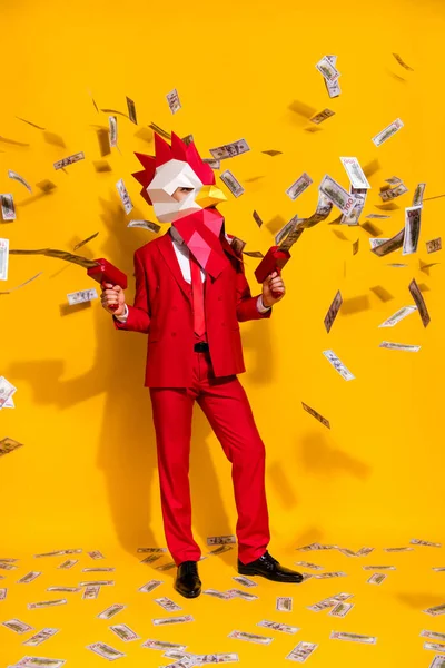 Függőleges fotó a furcsa fickó tartsa pénz fegyvert lő dollárt visel kakas sokszögletű maszk piros ruha izolált sárga háttér — Stock Fotó