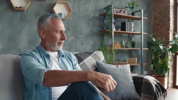 Positivo uomo di mezza età sedersi divan mobili godere di camera in casa — Video Stock