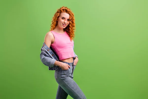 Foto de encantadora mujer joven bonita usar jeans traje gafas brazos bolsillo espacio vacío sonriendo aislado color verde fondo — Foto de Stock