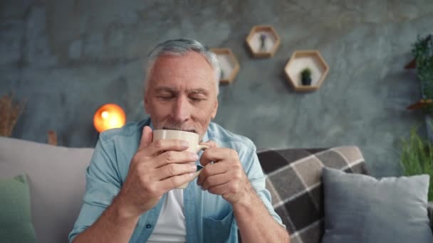 Pozitív nagyapa ül divan belső modern szoba, mint a koffein cappuccino — Stock videók