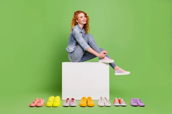 Full size profiel zijkant foto van jong meisje gelukkig positieve glimlach veters slijtage schoenen kopen verkoop geïsoleerd over groene kleur achtergrond — Stockfoto