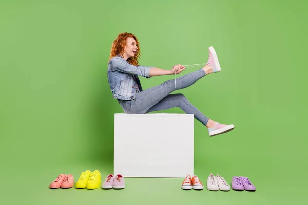 Volledig lichaam profiel zijkant foto van jong meisje gelukkig positief glimlach schoenveters slijtage sneakers winkel geïsoleerd over groene kleur achtergrond — Stockfoto