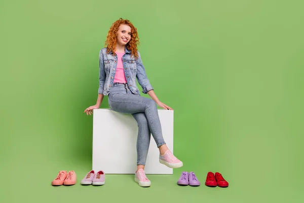 Pleine longueur photo de jeune fille attrayante heureux sourire positif sit store choisir des chaussures isolées sur fond de couleur verte — Photo