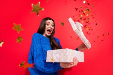 Photo of amazed shocked excited young woman hold hand box fly star confetti isolated on red color background clipart