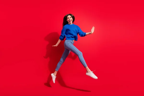 Perfil de cuerpo completo lado de la foto de la joven mujer feliz saltar de buen humor sonrisa caminar aislado sobre fondo de color rojo —  Fotos de Stock