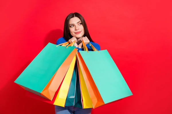 Fotografie veselý mladý pěkný atraktivní žena vzhled prázdný prostor držet prodej tašky izolované na červeném pozadí — Stock fotografie