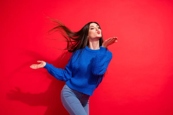 Foto de alegre funky jovem olhar segurar mão enviar ar beijo espaço vazio mosca cabelo isolado no fundo de cor vermelha — Fotografia de Stock