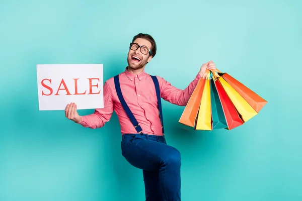 Photo of pretty funky young gentleman wear pink shirt glasses holding sale card bargains smiling isolated teal color background — Stock Photo, Image