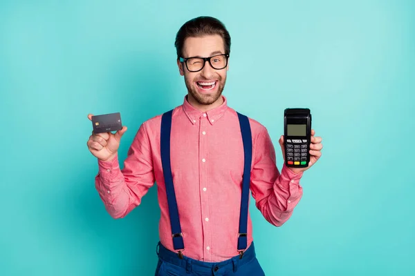 Foto van vrij charmante heer dragen roze shirt bril met credit card terminal knipogen glimlachen geïsoleerde teal kleur achtergrond — Stockfoto