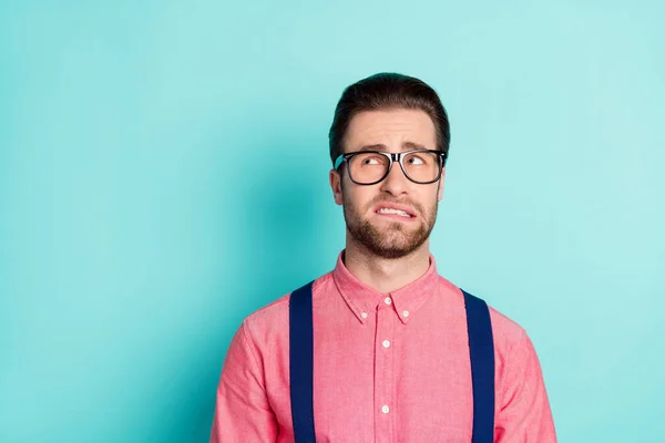 Foto van twijfelachtige ongelukkige overstuur jongeman kijken lege ruimte dragen bril bijten tanden geïsoleerd op teal kleur achtergrond — Stockfoto