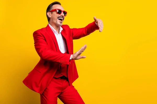 Zdjęcie uśmiechniętego pozytywnego faceta tańczącego wokół siebie w dobrze ubranym garniturze formalwear odizolowanym na żółtym tle — Zdjęcie stockowe