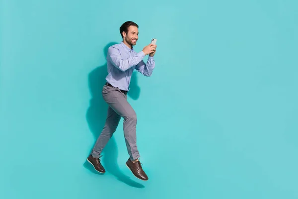 Foto do viciado em mídia social homem salto movimento ler telefone feedback desgaste camisa violeta isolado turquesa cor fundo — Fotografia de Stock