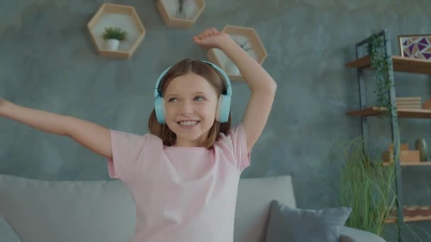 Schoolchild enjoy pop melody device headset dance active jump in living room — Stock Video