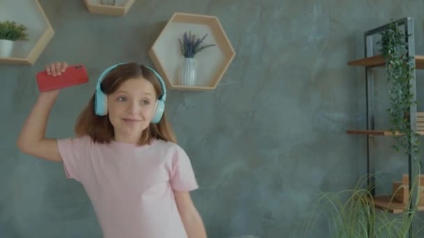 Schoolkind luisteren dynamische melodie headset gadget springen bank in kamer flat — Stockvideo