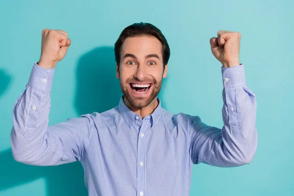 Фото изумленного парня поднимает кулаки радуются удачной инвестиционной возможности носить фиолетовую рубашку изолированного бирюзового цвета фона — стоковое фото