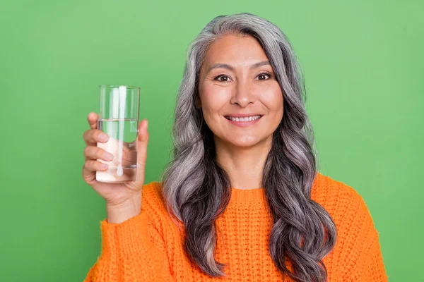 Foto di bella donna anziana acconciatura bianca tenere l'acqua usura maglione arancione isolato su sfondo verde — Foto Stock