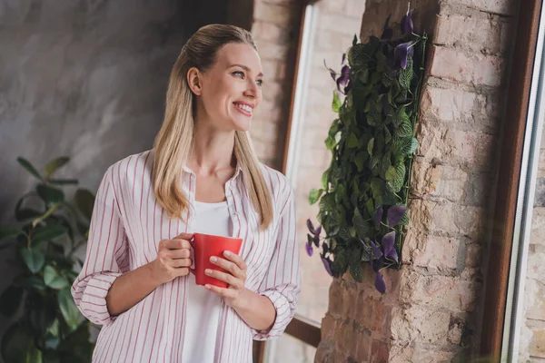 Фото оптической юной блондинки говорить пить чай носить полосатую рубашку выходные каникулы в гостиной в одиночку — стоковое фото