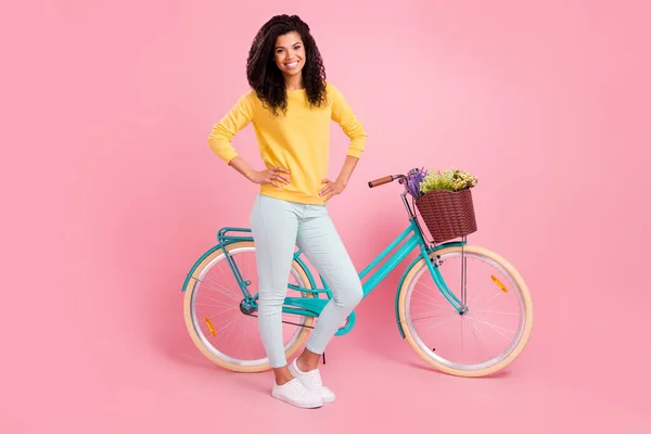 Longitud completa vista del tamaño del cuerpo de bastante contenido chica alegre con las manos de bicicleta en las caderas aisladas sobre fondo de color rosa pastel —  Fotos de Stock