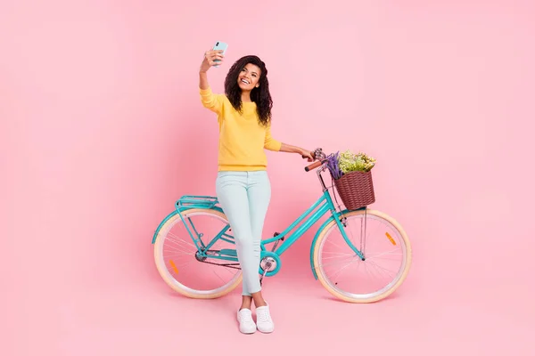 Comprimento total do corpo tamanho vista de menina alegre muito na moda com bicicleta tomando selfie se divertindo isolado sobre pastel cor-de-rosa fundo — Fotografia de Stock