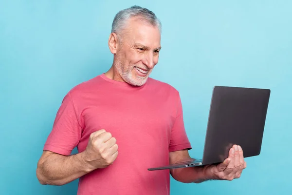 Foto retrato homem mais velho sorrindo usando laptop navegação internet gesturing como vencedor isolado pastel azul cor de fundo — Fotografia de Stock