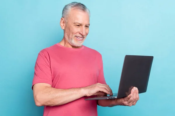 Zdjęcie portret brodatego człowieka różowy t-shirt za pomocą laptopa przeglądanie Internetu odizolowane pastel niebieski kolor tło — Zdjęcie stockowe