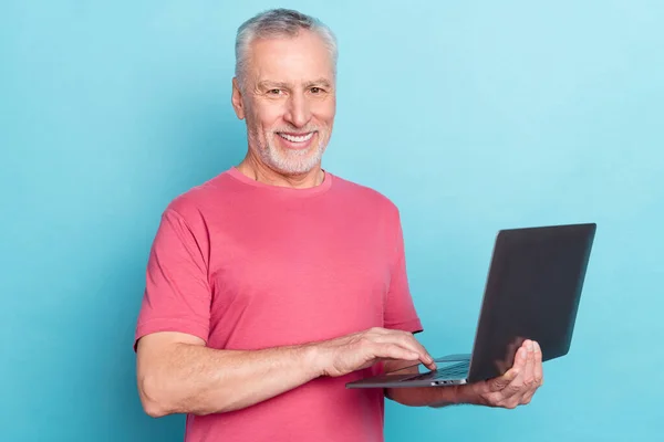 Zdjęcie portret starszy człowiek uśmiecha się za pomocą laptopa przeglądanie Internetu odizolowany pastel niebieski kolor tło — Zdjęcie stockowe