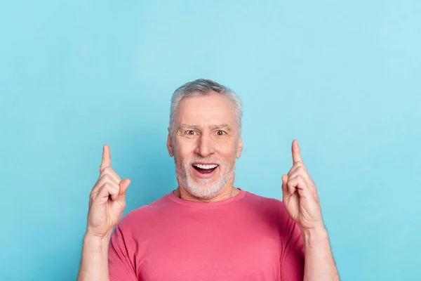 Foto retrato senior hombre sorprendido divertido apuntando dedo copyspace hasta soñador aislado pastel azul color fondo —  Fotos de Stock