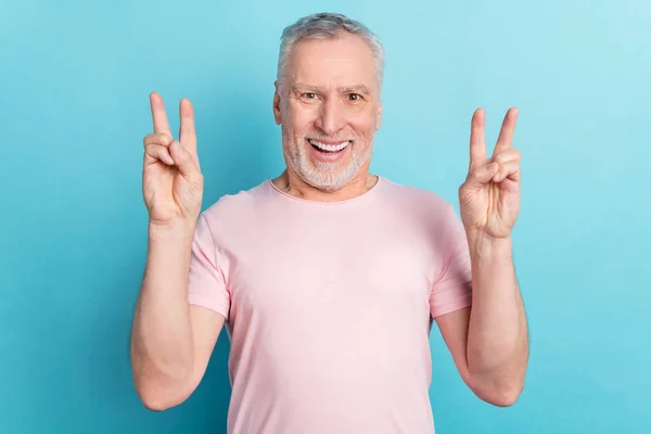 写真はパステルブルーの背景に孤立したvサインジェスチャーを示すピンクのTシャツの老人の笑顔肖像画 — ストック写真
