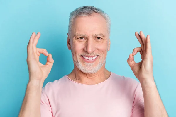 Φωτογραφία πορτρέτο του γενειοφόρου άνδρα ροζ t-shirt χαμογελώντας δείχνει εντάξει σημάδι απομονώνονται σε παστέλ μπλε χρώμα φόντο — Φωτογραφία Αρχείου