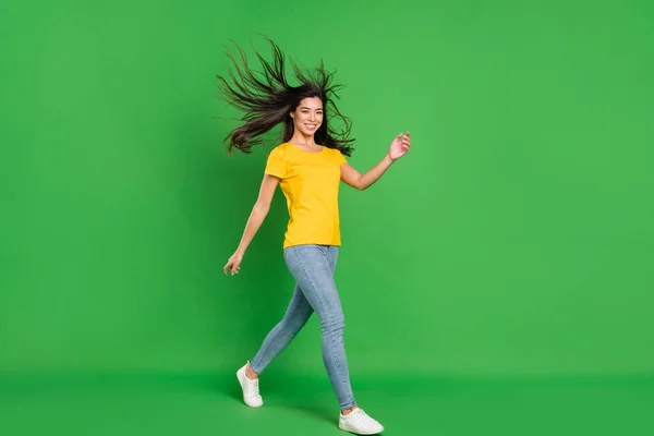 Photo de charmante jeune femme joyeuse marcher espace vide voler week-end de cheveux isolé sur fond de couleur verte — Photo