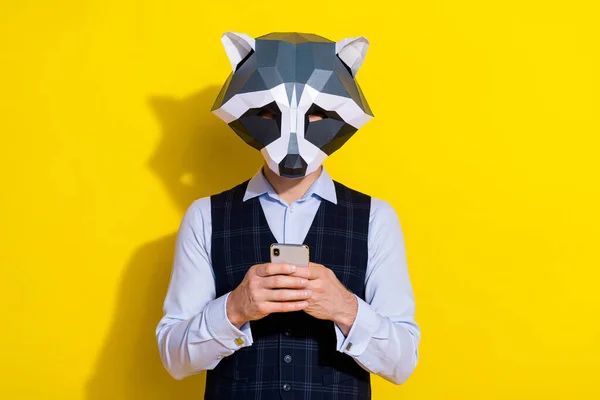 Fotografie populárního chlapa držet telefon použití app číst zpětnou vazbu nosit mývalí maska vesta izolované žluté barvy pozadí — Stock fotografie