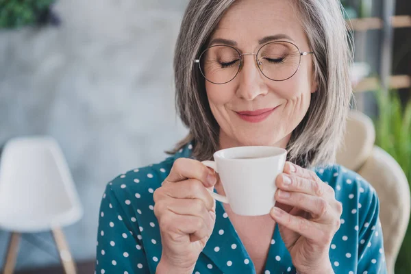 Обрезанное фото привлекательной пожилой женщины счастливая позитивная улыбка мечта мечтательный насладиться запахом аромат утреннего кофе в помещении — стоковое фото