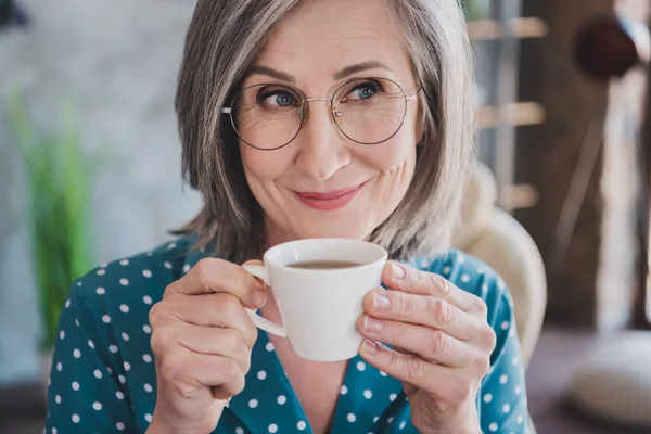 Gewassen foto van aantrekkelijke oudere vrouw gelukkig positieve glimlach droom dromerig drinken koffie thee pauze pauze binnen — Stockfoto