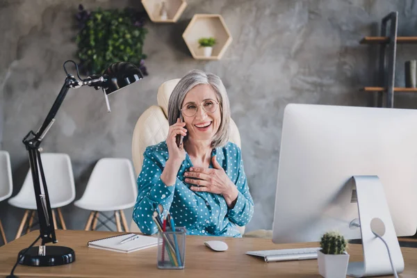 Фото счастливой фанки положительный старуха говорить по телефону смеяться хорошая шутка в помещении дома офис рабочее место — стоковое фото