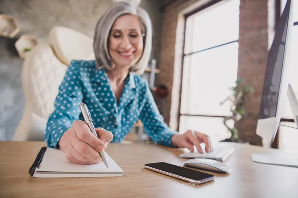 Foto van vrolijke vrolijke vrij mooie oude vrouw schrijf plan in notebook glimlach binnen op kantoor werkplek — Stockfoto