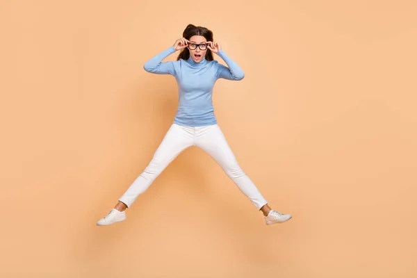 Full storlek foto av imponerad ung dam hoppa bära glasögon tröja byxor skor isolerad på beige bakgrund — Stockfoto