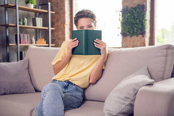 Foto de adorable niña niña usar amarillo camiseta libro cubierta cara interior habitación casa — Foto de Stock