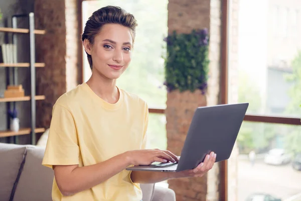 Fotografie okouzlující roztomilá dáma držet počítač ruka klávesnice úsměv nosit žluté tričko v moderním domě uvnitř — Stock fotografie