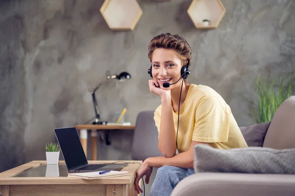 Foto de doce bonita jovem senhora usar amarelo t-shirt sentado sofá digitando gadget moderno falando microfone dentro de casa quarto — Fotografia de Stock