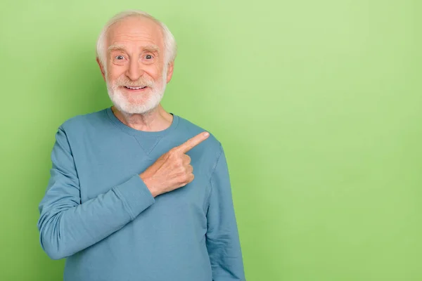 Foto van optimistische oudere baard man index promo slijtage blauwe trui geïsoleerd op groene kleur achtergrond — Stockfoto