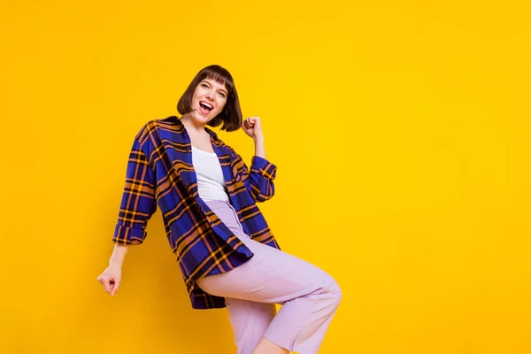 Retrato de menina alegre sorte atraente dançando se divertindo vestindo camisa xadrez isolado sobre fundo de cor amarela brilhante — Fotografia de Stock