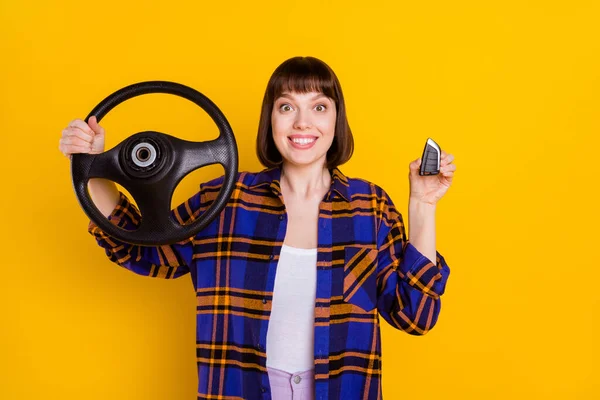 Portrait d'une jolie fille gaie et étonnée tenant le volant verrouillage clé isolé sur fond jaune vif — Photo